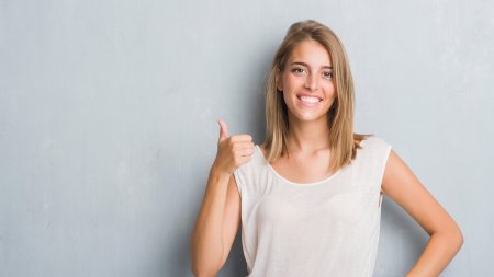 Mujer sonriendo con fondo de pared gris