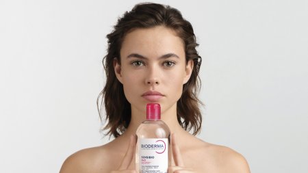 Mujer sonriendo mostrando producto de agua micelar Mujer sonriendo mostrando producto de agua micelar